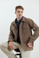 Sobrecamisa de tejido grueso sin forro, con diseño de corte holgado y silueta cuadrada. Presenta cuello clásico, cierre frontal con botones mate y dos bolsillos en el pecho con solapa.