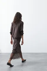 Falda midi negra de caída fluida con cintura elastizada y un amplio detalle de encaje negro en el bajo.