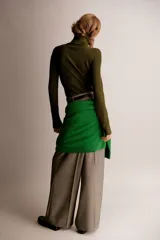 Top de manga larga en punto acanalado color verde oliva, con cuello alto y cierre frontal parcial metálico. El calce es ajustado y el bajo es recto.