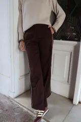Pantalón de corte sastre con pierna recta, color marrón chocolate, con detalle de rayas laterales en contraste.