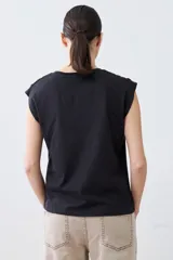 Remera color pistacho con cuello en V y botones decorativos en los hombros.