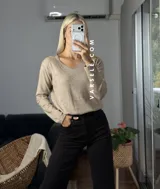 Sweater de punto color bordó con escote en V y detalle de strass aplicado en la parte frontal. Presenta mangas largas y corte holgado.