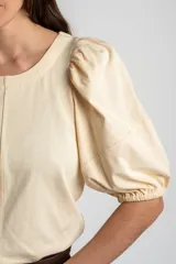 Remera de algodón negro con mangas cortas abullonadas, cuello redondo y costura central frontal.