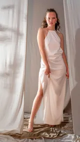 Vestido largo blanco de satén con cuello halter y tajo lateral.