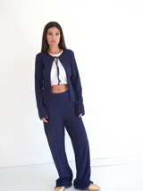 Saco de punto acanalado color azul marino, con mangas largas y cierre frontal mediante lazo ajustable en el cuello.