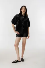 Short negro de cuero de oveja, de tiro alto con tablas, bolsillos laterales y cierre frontal con gancho.