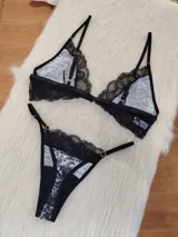 Conjunto de lencería compuesto por corpiño triangular y bombacha tipo tanga. El diseño combina microtul con estampado animal print y detalles de encaje negro en los bordes. El corpiño cuenta con cierre frontal y breteles regulables.