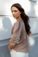 Blusa blanca de algodón suave, con mangas 3/4 y escote redondo con volados en el frente, mangas y escote.