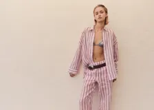 Camisa de corte oversize confeccionada en tejido de ramio, con diseño de rayas verticales en tonos rosados y oscuros. Presenta cuello camisero clásico, cierre frontal con botones y mangas largas con puños.