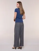 Remera básica de corte al cuerpo con textura acanalada, cuello redondo y mangas cortas. Presenta una pequeña placa metálica decorativa en el borde inferior.
