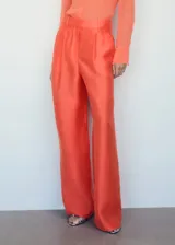 Pantalon de corte wideleg color naranja, confeccionado en mezcla de lino y lyocell. Presenta diseño de tiro alto con trabillas para cinturón, pinzas frontales, dos bolsillos laterales y dos bolsillos de ribete en la parte posterior. Cierre oculto de botón, gancho y cremallera.
