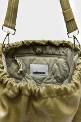 Bolso tipo hobo confeccionado en cuero vacuno color verde militar, con diseño fruncido en la parte superior y cierre con cordón ajustable. Cuenta con una correa larga regulable y desmontable sujeta por mosquetones metálicos.
