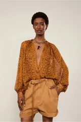 Camisa de mangas largas y amplias con estampado animal print, cierre de botones frontal y cuello padre con detalle fruncido.