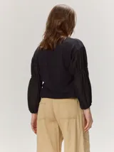 Remera blanca con cuerpo de algodón liso y mangas abullonadas semitransparentes con textura de lunares.