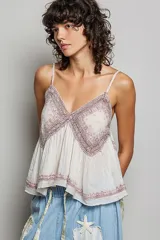 Top de algodón color rosado, con escote en V, tirantes finos, detalles de encaje bordado en el pecho y bajo asimétrico fluido.