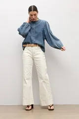 Camisa de jean de corte clásico con cuello mao, cierre frontal con botones y mangas largas abullonadas con puños elásticos.