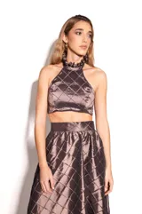 Top corto color marrón con diseño acolchado de rombos, escote halter con volados y espalda descubierta con cierre de botones.