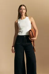 Jean de corte wide leg y tiro alto, color negro con costuras en contraste color ocre. Presenta bolsillos delanteros y traseros con detalle de pespunte, y ruedo ancho con costura decorativa.