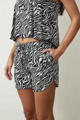 Shorts de mujer color negro con estampado de piel de serpiente, tiro alto y cordón ajustable en la cintura.