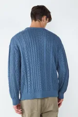 Sweater de punto color azul, con cuello redondo, manga larga y diseño de tejido a cables. Presenta detalles de cordones decorativos en el ruedo.