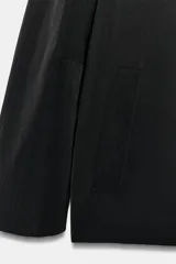 Blazer cruzado Zara de color negro, con cuello de solapa, manga larga y bolsillos laterales ocultos en la costura. Cuenta con cierre frontal de botones.