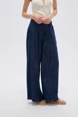 Pantalón jean azul de tiro medio, corte holgado y diseño amplio con pinzas en la parte frontal.