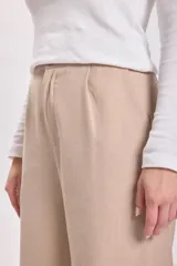 Pantalón de vestir de corte ancho y tiro alto, con pinzas delanteras y bolsillos laterales.
