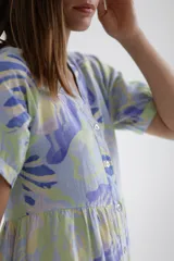 Vestido midi celeste con estampado de hojas en tonos lila y verde, corte evasé, cuello camisero, manga corta y falda escalonada.