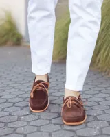 Zapato náutico de cuero gamuzado color marrón chocolate, con cordones y suela plana.
