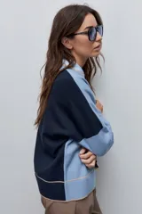 Sweater tejido celeste de calce relajado con cuello redondo, hombros caídos y puños y ruedo acanalados con detalles en tono tostado.