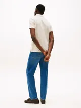 Chomba Tommy Hilfiger color crema con estampado de hojas en tono beige, cuello clásico, solapa de dos botones, corte regular y logo bordado en el pecho.