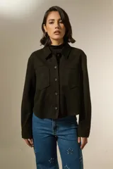 Sobrecamisa de estilo casual en color negro, confeccionada en tejido tipo gamuza. Presenta cuello clásico, cierre frontal con botones, dos bolsillos frontales tipo parche y mangas largas con puños abotonados.