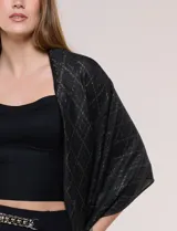 Pashmina rectangular negra con diseño jacquard de rombos, destellos metalizados dorados y flecos anudados en los extremos.