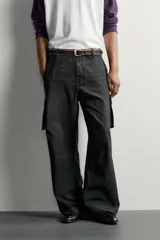 Pantalón cargo de corte relaxed fit, color negro con efecto lavado y estampado de salpicaduras blancas. Cuenta con bolsillos laterales con solapa en las perneras, pinzas en las rodillas y cierre frontal con botón y cremallera.