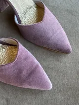 Zapatos de tacón bajo en tela color malva, con punta fina, taco ancho de 5 cm, escote en V y tiras cruzadas en diagonal con cierre de hebilla en el tobillo.