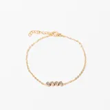 Pulsera de cadena fina dorada con cinco piedras de cristal redondas engastadas en línea. Cuenta con cierre de mosquetón y cadena de ajuste.