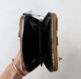 Billetera cuadrada con cierre de cremallera y estampado de vaca en blanco y negro o blanco y marrón.