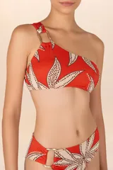 Top de bikini asimétrico color naranja con estampado abstracto en tonos beige y negro. Tiene un solo tirante con detalle de aro de madera.
