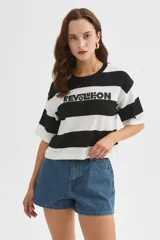Remera cropped de algodón con diseño de rayas horizontales en blanco y negro, cuello redondo y manga corta. Cuenta con un estampado con la inscripción "REVOLUTION" en el pecho.