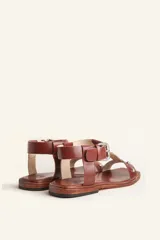 Sandalias negras de cuero con tiras finas, pulsera al tobillo con hebilla metálica y apliques de tachas plateadas.