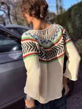 Sweater tejido a mano en hilo de algodón color crudo, con diseño geométrico en colores azul, rojo, verde y marrón en la parte superior.