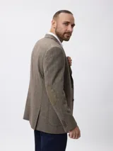 Blazer de tweed color azul marino con coderas en contraste, cierre frontal de botones y bolsillos laterales. Presenta un diseño clásico de corte regular.