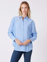 Camisa de algodón con estampado de rayas verticales finas en color azul claro. Tiene cuello con solapa, escote en V y cierre frontal con botones.