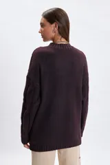 Sweater de punto con diseño de trenzas verticales, cuello redondo y mangas largas. Presenta un corte holgado y terminaciones acanaladas en cuello, puños y ruedo.