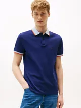 Chomba azul marino de algodón elástico, con cuello tejido a contraste en blanco y gris con ribete naranja. Tiene tapeta de dos botones, mangas cortas con ribete a contraste y logo de Tommy Hilfiger bordado en el pecho.