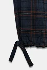 Pantalón cargo de tiro medio con estampado de cuadros, bolsillos laterales tipo cargo con solapa y bajo ajustable con cordones. Cuenta con cierre frontal de cremallera y botón.