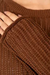 Suéter de tejido calado en color café, con cuello redondo, mangas largas y diseño corto de silueta holgada.