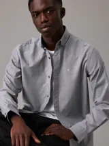 Camisa de vestir gris claro de corte regular, confeccionada en tejido Oxford de algodón y elastano, con cierre frontal abotonado, mangas largas y logo CK bordado en el pecho.