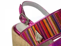 Sandalias de plataforma corrida revestida en corcho, con tiras delanteras de cuero fucsia brillante y tira ancha superior con detalles textiles multicolor estilo aguayo. Presenta cierre con hebilla en el talón.