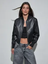Campera bomber de eco cuero negro, con cierre frontal plateado, cuello, puños y cintura elastizados en rib.